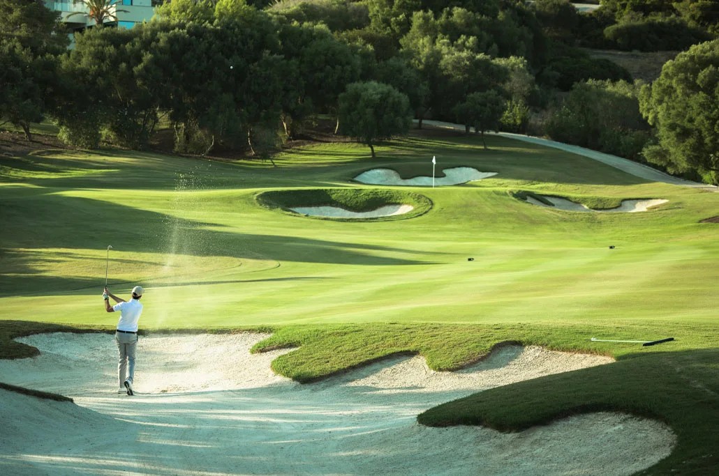 Green beside a lake at La Reserva Club Sotogrande at sunset