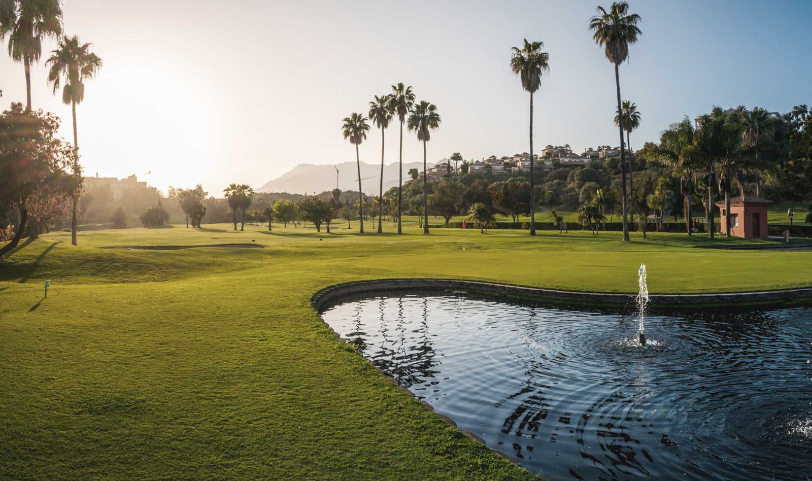 Santa Clara Golf Marbella fairway with manicured greens and palm trees under blue sky