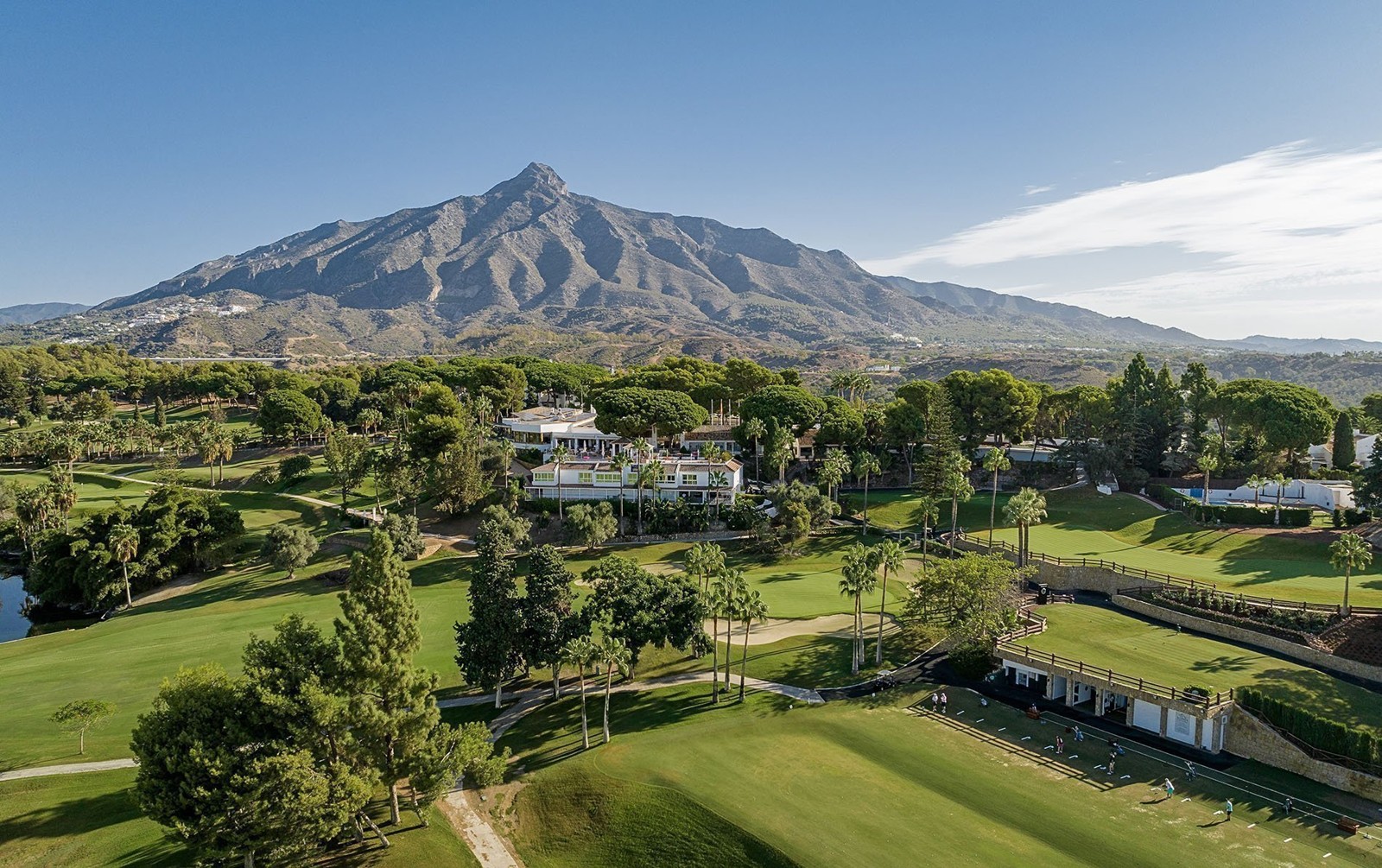 Palm-lined parkland fairway at Aloha Golf Club with mountains behind
